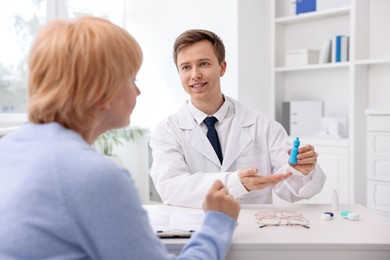 Photo of Ophthalmologist consulting senior woman at white table in clinic