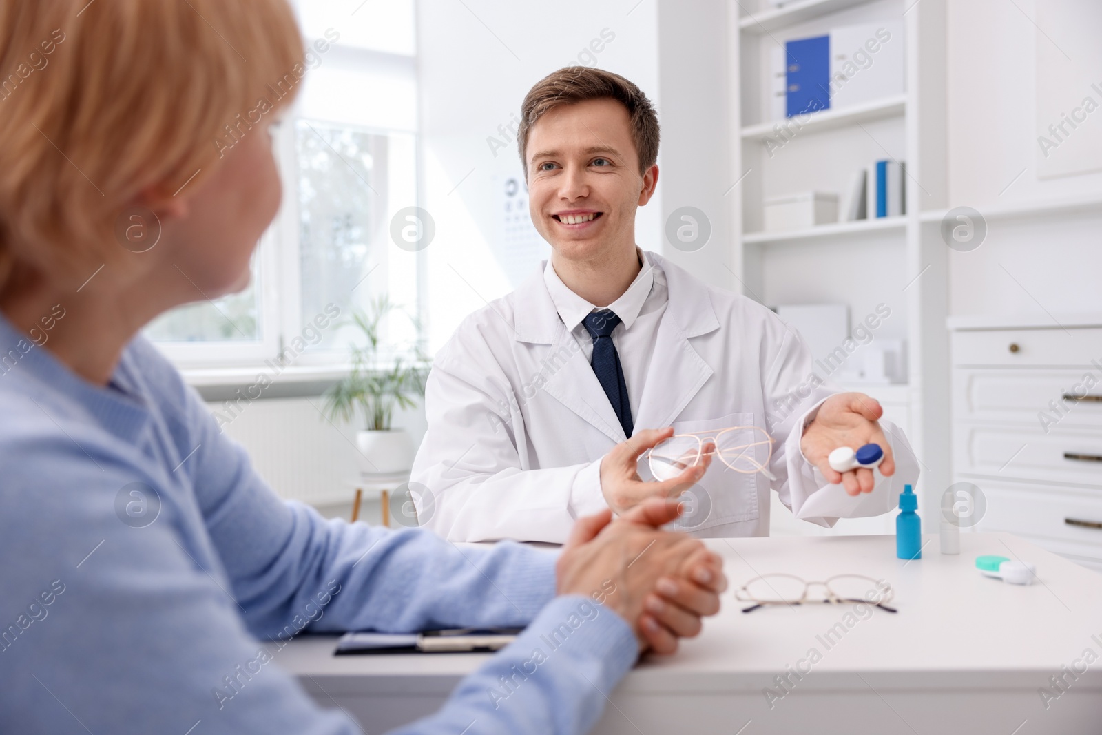 Ophthalmologist consulting senior woman at white table in clinic Photo of Ophthalmologist consulting senior woman at white table in clinic