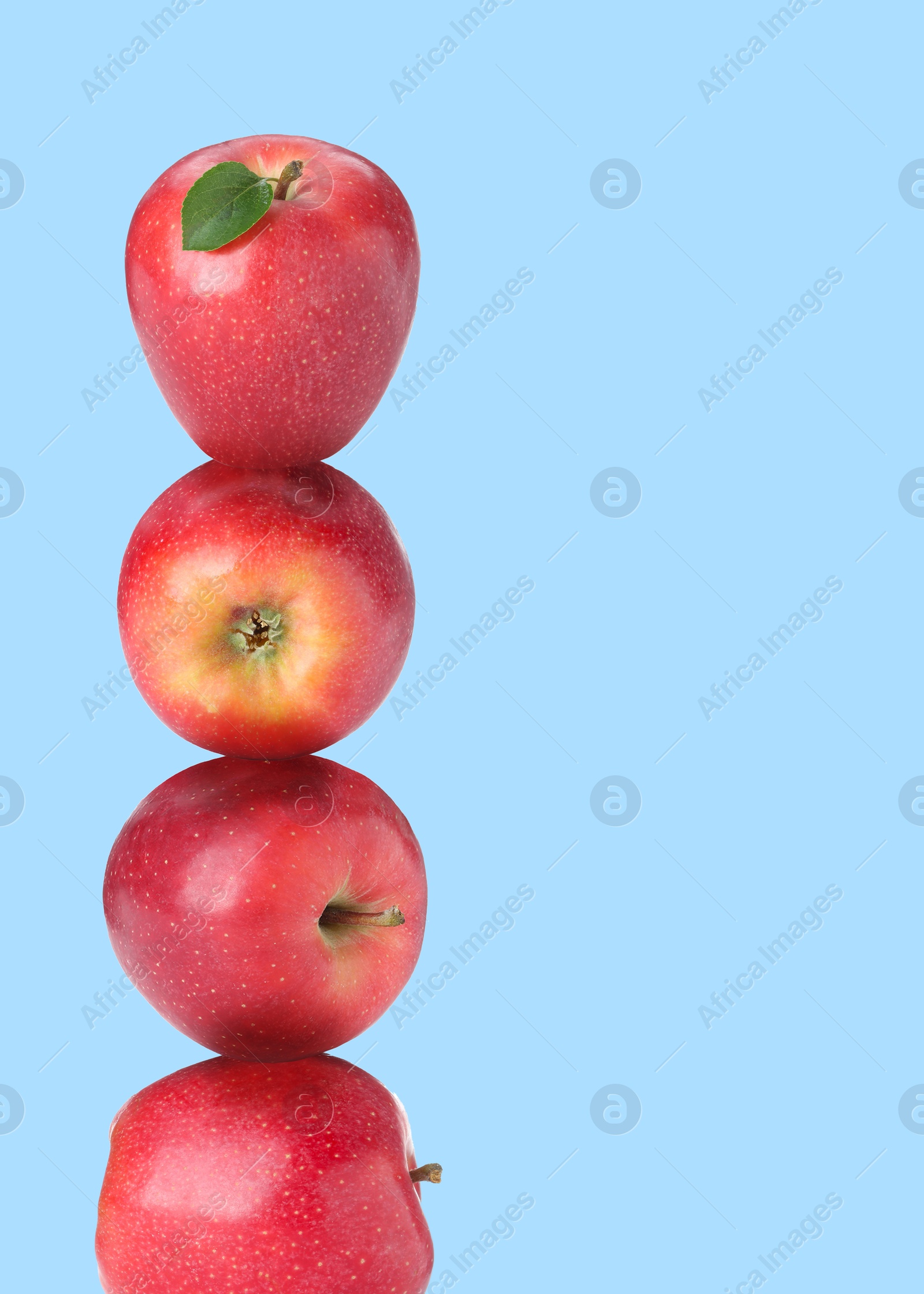 Red apples stacked on top of each other against light blue background. Balance Image of Red apples stacked on top of each other against light blue background. Balance