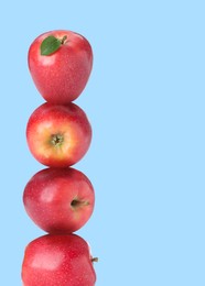Image of Red apples stacked on top of each other against light blue background. Balance
