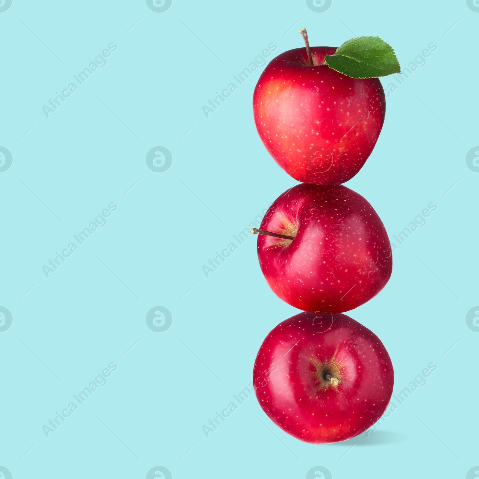 Red apples stacked on top of each other against light blue background. Balance Image of Red apples stacked on top of each other against light blue background. Balance