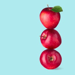 Image of Red apples stacked on top of each other against light blue background. Balance