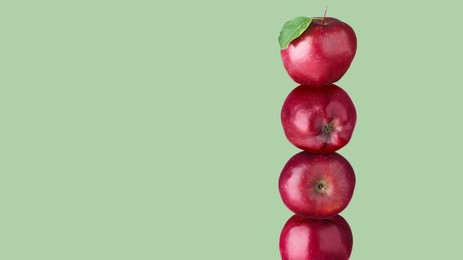 Image of Red apples stacked on top of each other against sage color background. Balance