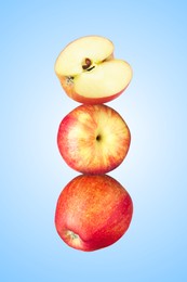 Image of Apples stacked on top of each other against light blue background. Balance
