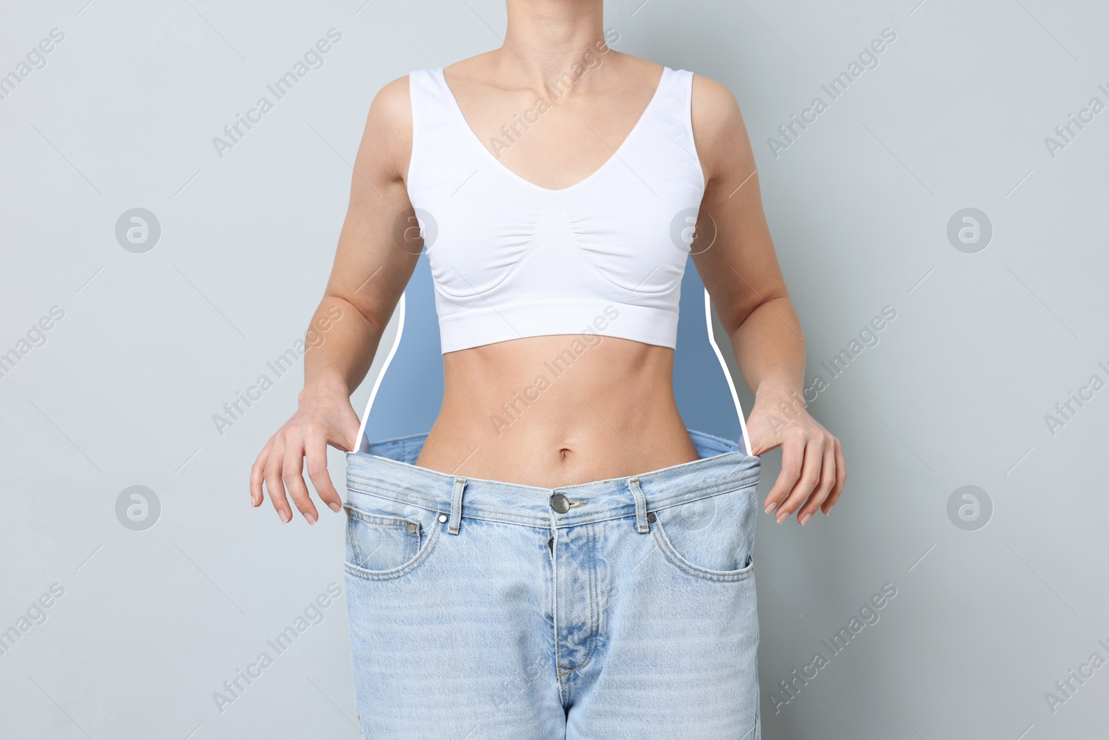 Slim woman with perfect body in oversized jeans on grey background, closeup. Outline of previous overweight figure around. Result of healthy lifestyle Image of Slim woman with perfect body in oversized jeans on grey background, closeup. Outline of previous overweight figure around. Result of healthy lifestyle