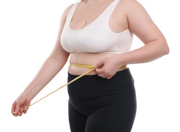Photo of Weight loss. Plus size woman measuring waist with tape on white background, closeup