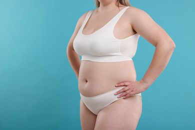 Photo of Weight loss. Plus size woman in underwear on light blue background, closeup