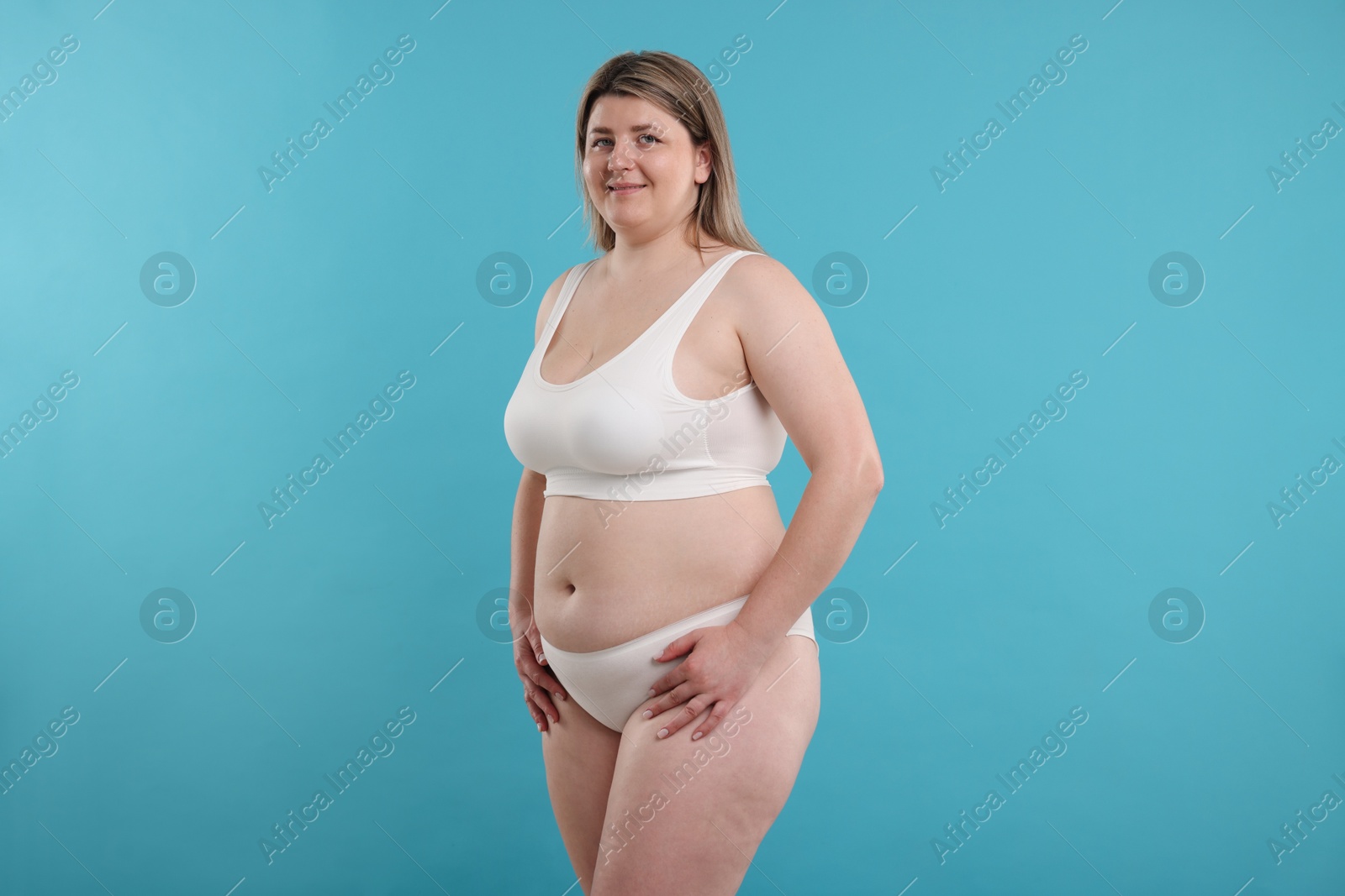 Weight loss. Plus size woman in underwear on light blue background Photo of Weight loss. Plus size woman in underwear on light blue background