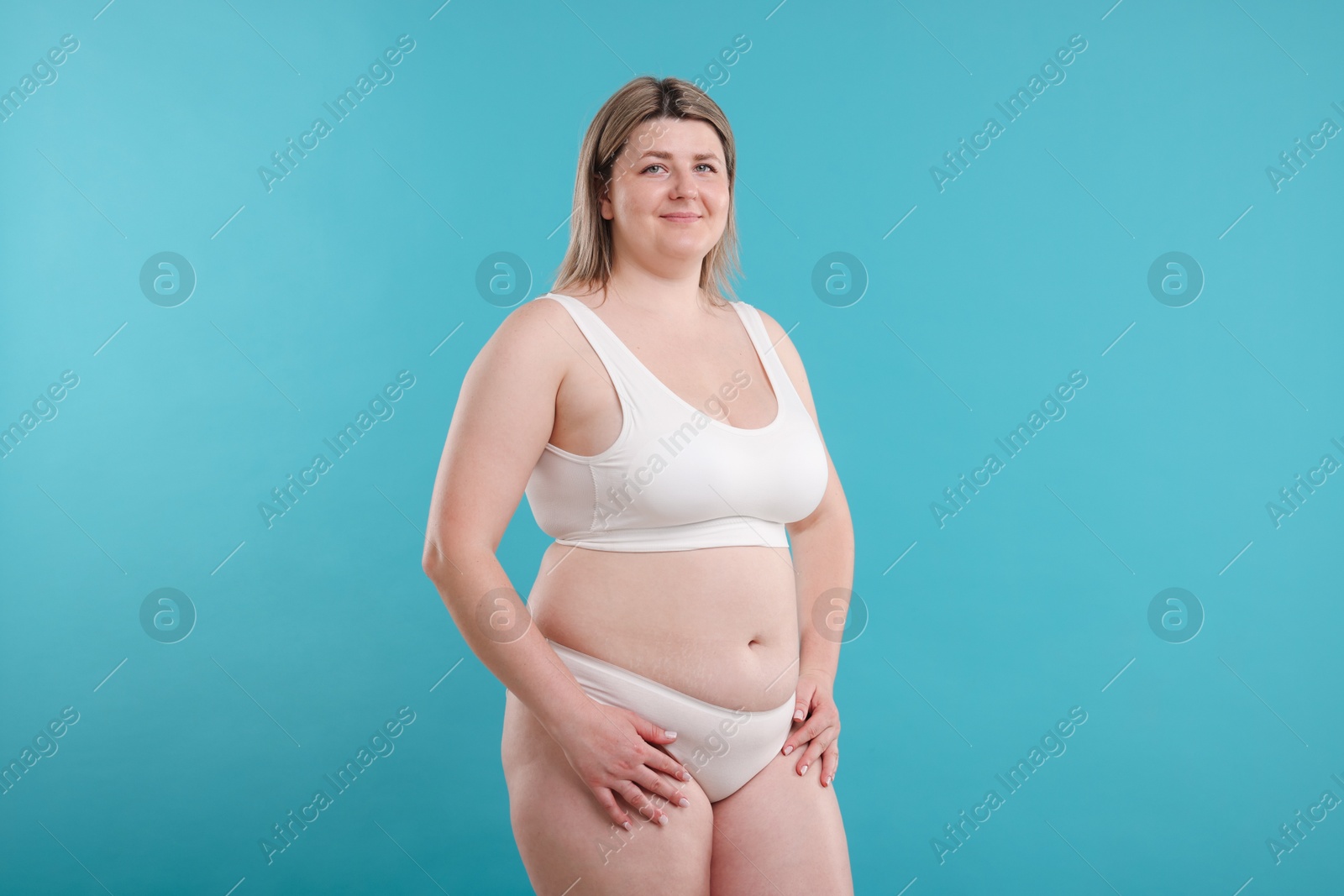 Weight loss. Plus size woman in underwear on light blue background Photo of Weight loss. Plus size woman in underwear on light blue background