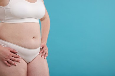 Photo of Weight loss. Plus size woman in underwear on light blue background, closeup. Space for text