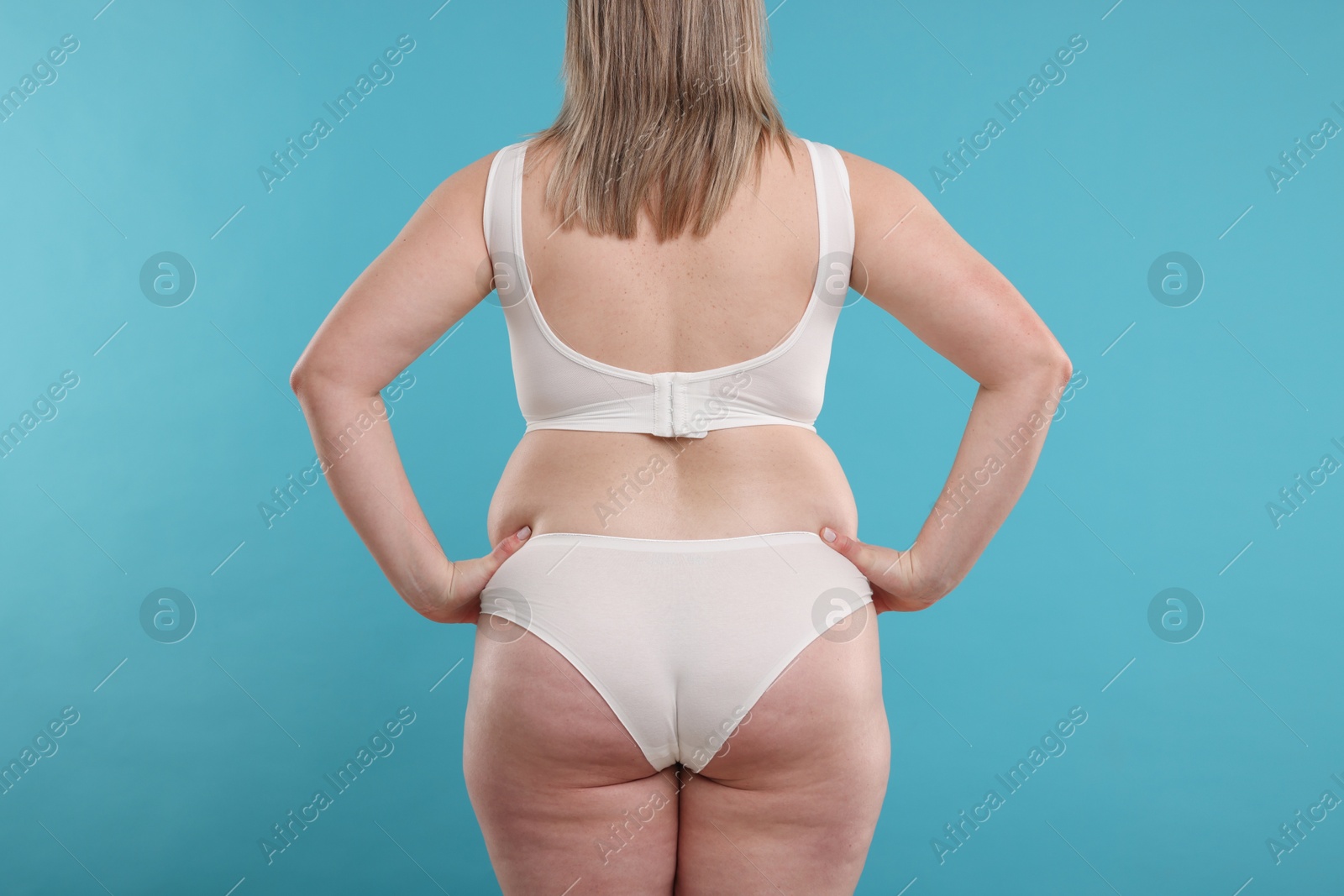 Weight loss. Plus size woman in underwear on light blue background, back view Photo of Weight loss. Plus size woman in underwear on light blue background, back view