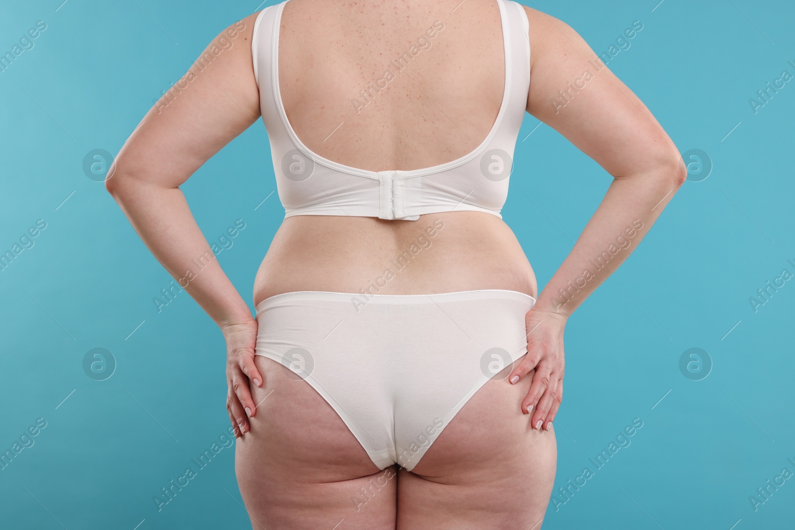 Weight loss. Plus size woman in underwear on light blue background, closeup Photo of Weight loss. Plus size woman in underwear on light blue background, closeup