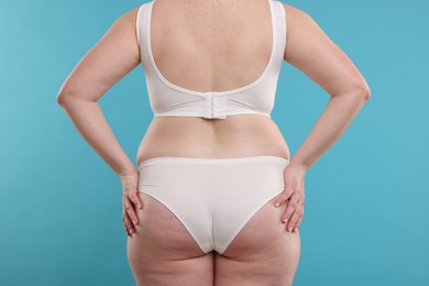 Photo of Weight loss. Plus size woman in underwear on light blue background, closeup