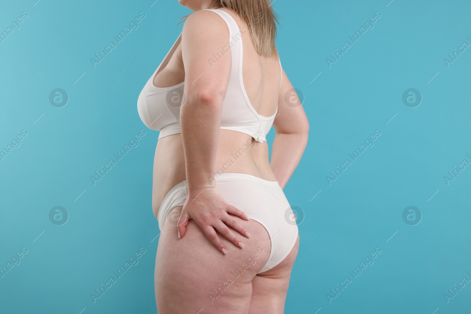 Weight loss. Plus size woman in underwear on light blue background, closeup Photo of Weight loss. Plus size woman in underwear on light blue background, closeup