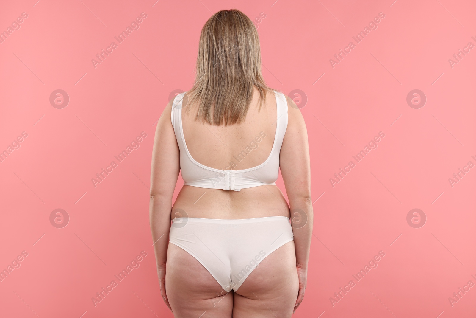 Weight loss. Plus size woman in underwear on pink background, back view Photo of Weight loss. Plus size woman in underwear on pink background, back view