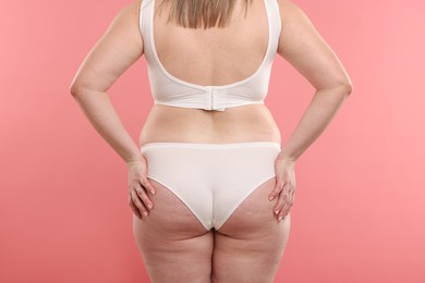 Photo of Weight loss. Plus size woman in underwear on pink background, closeup