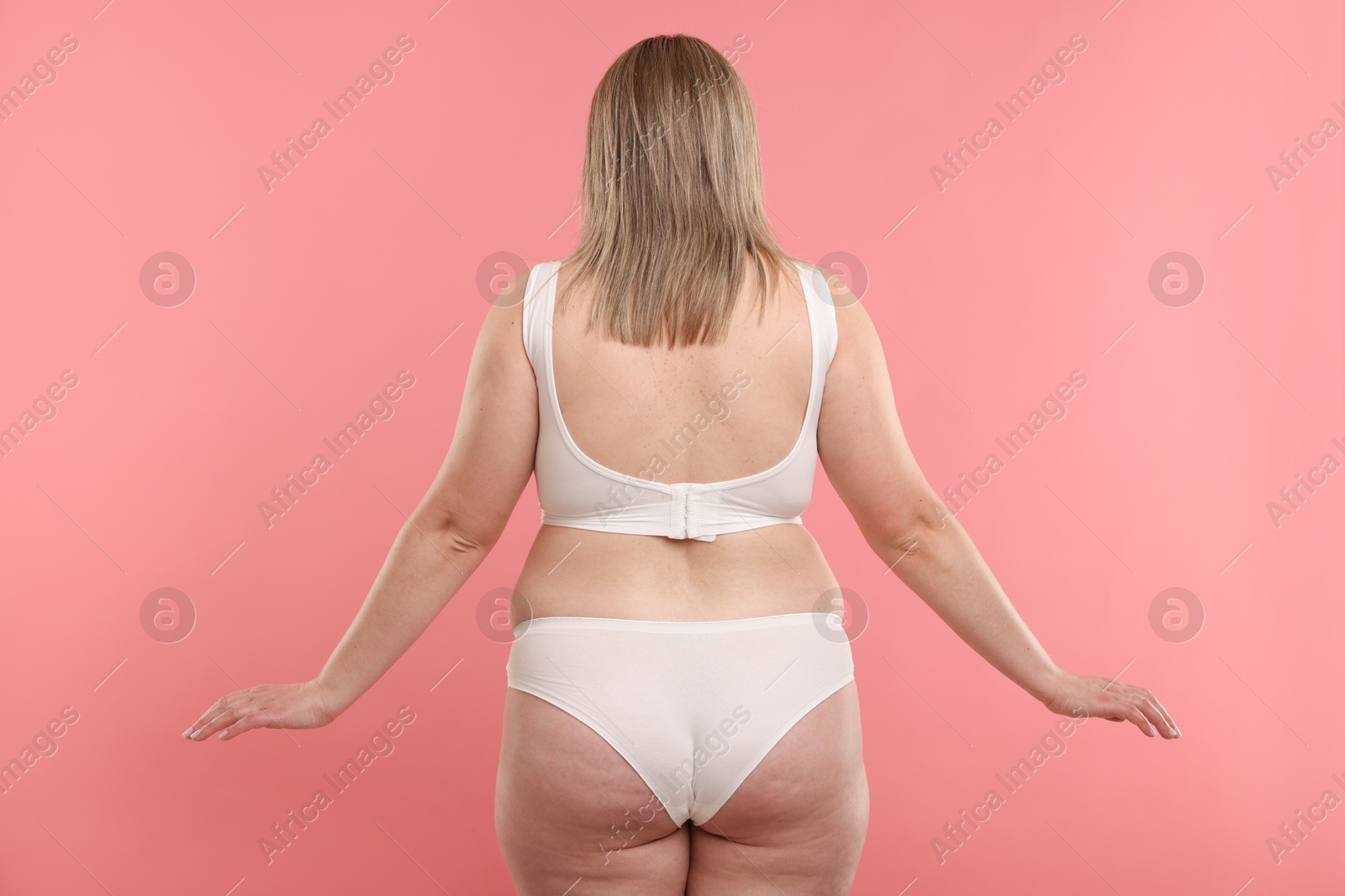 Weight loss. Plus size woman in underwear on pink background, back view Photo of Weight loss. Plus size woman in underwear on pink background, back view