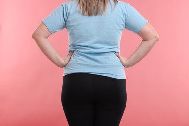 Photo of Weight loss. Plus size woman on pink background, closeup