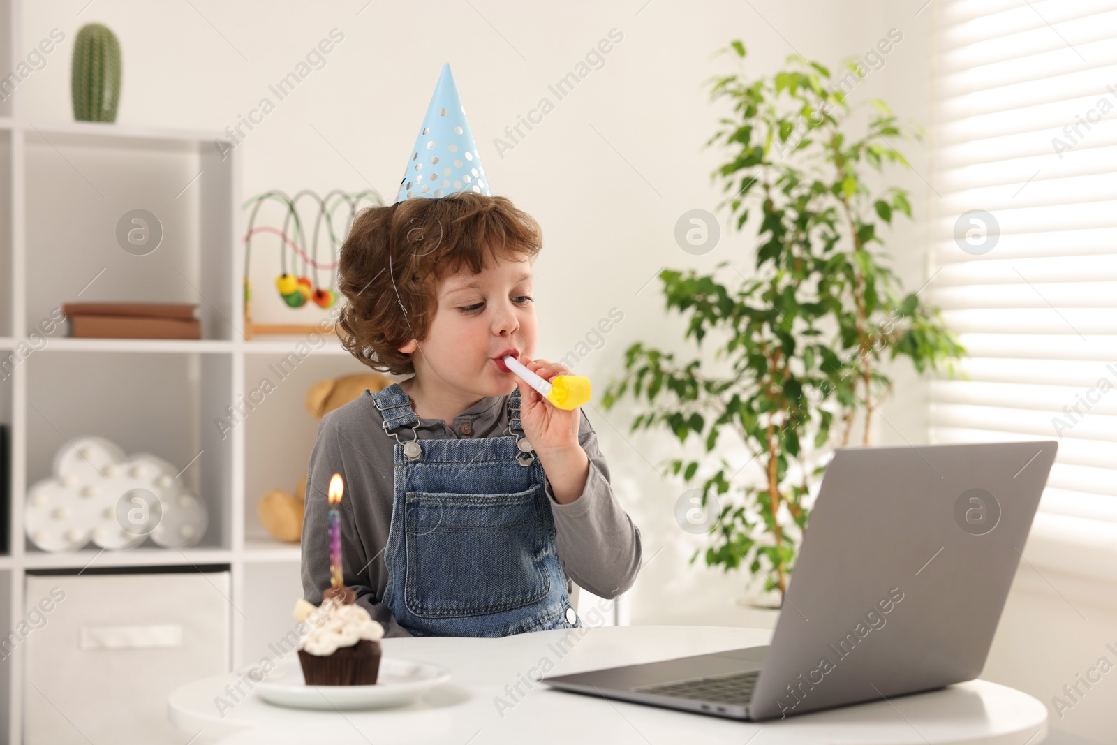 Little boy celebrating his birthday while having video call via laptop at table indoors Photo of Little boy celebrating his birthday while having video call via laptop at table indoors