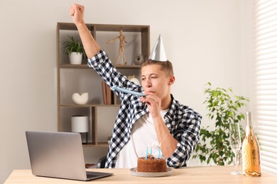 Photo of Happy man celebrating his birthday while having video call at desk indoors