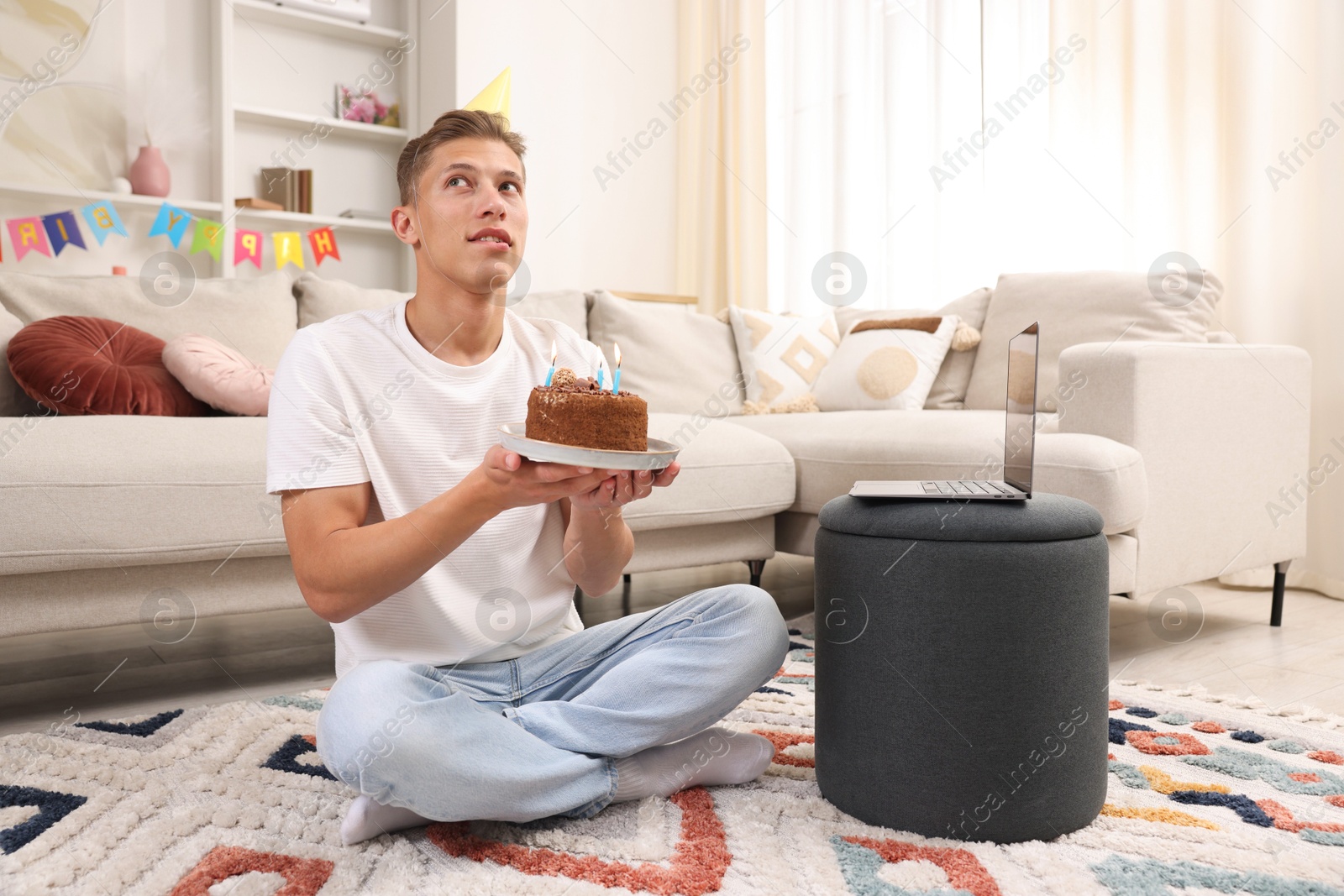 Birthday celebration. Man with cake making wish while having video call via laptop at home Photo of Birthday celebration. Man with cake making wish while having video call via laptop at home