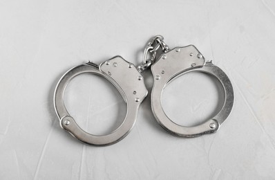 Photo of Handcuffs on light grey table, top view. Police equipment