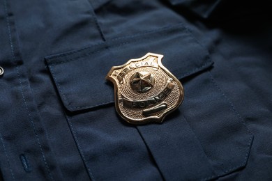 Photo of Police badge on dark blue uniform, closeup