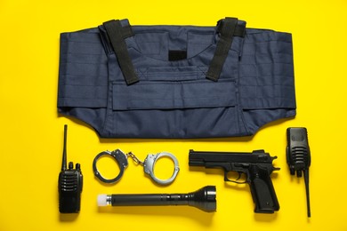 Photo of Different police equipment on yellow background, flat lay