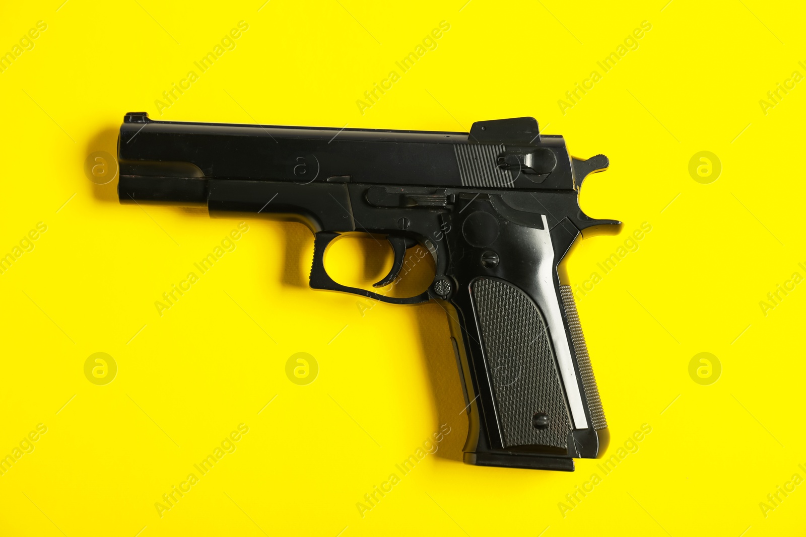 One black gun on yellow background, top view. Police equipment Photo of One black gun on yellow background, top view. Police equipment