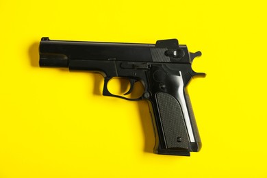 Photo of One black gun on yellow background, top view. Police equipment