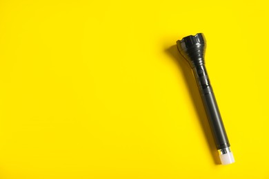 Photo of Police equipment. One flashlight on yellow background, top view. Space for text