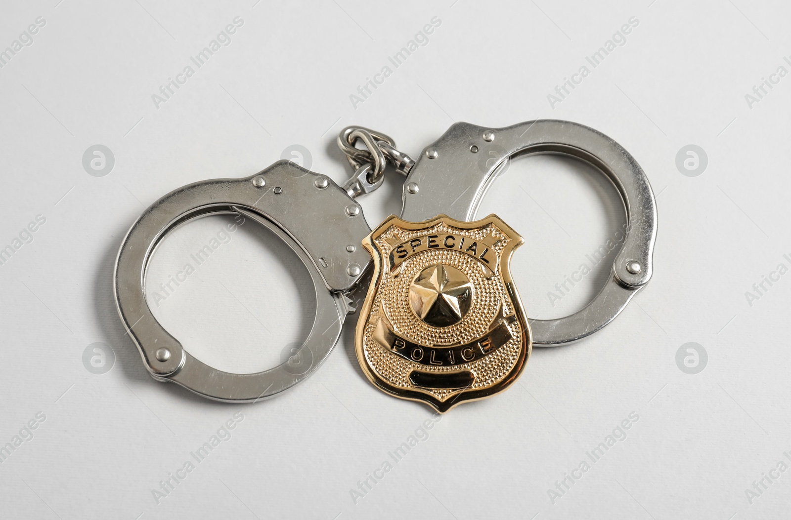 Police badge and handcuffs on white background, flat lay Photo of Police badge and handcuffs on white background, flat lay