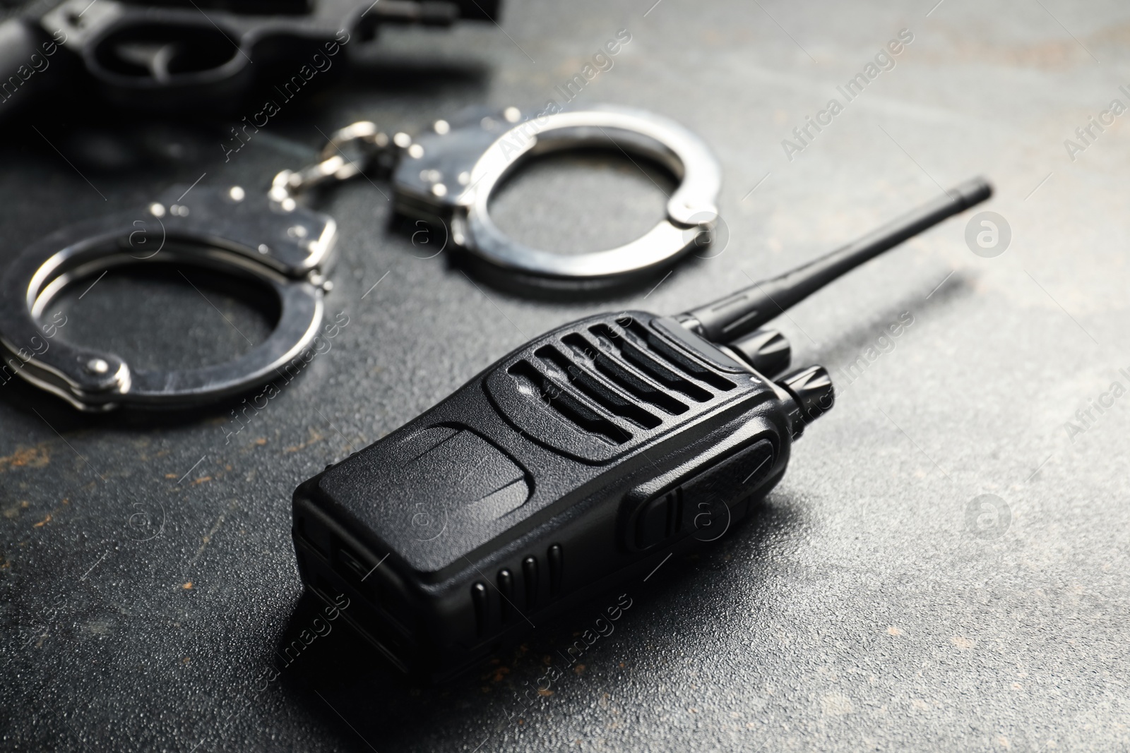 Walkie talkie, handcuffs and gun on dark table, closeup. Police equipment Photo of Walkie talkie, handcuffs and gun on dark table, closeup. Police equipment
