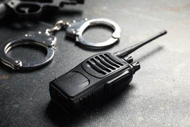 Photo of Walkie talkie, handcuffs and gun on dark table, closeup. Police equipment