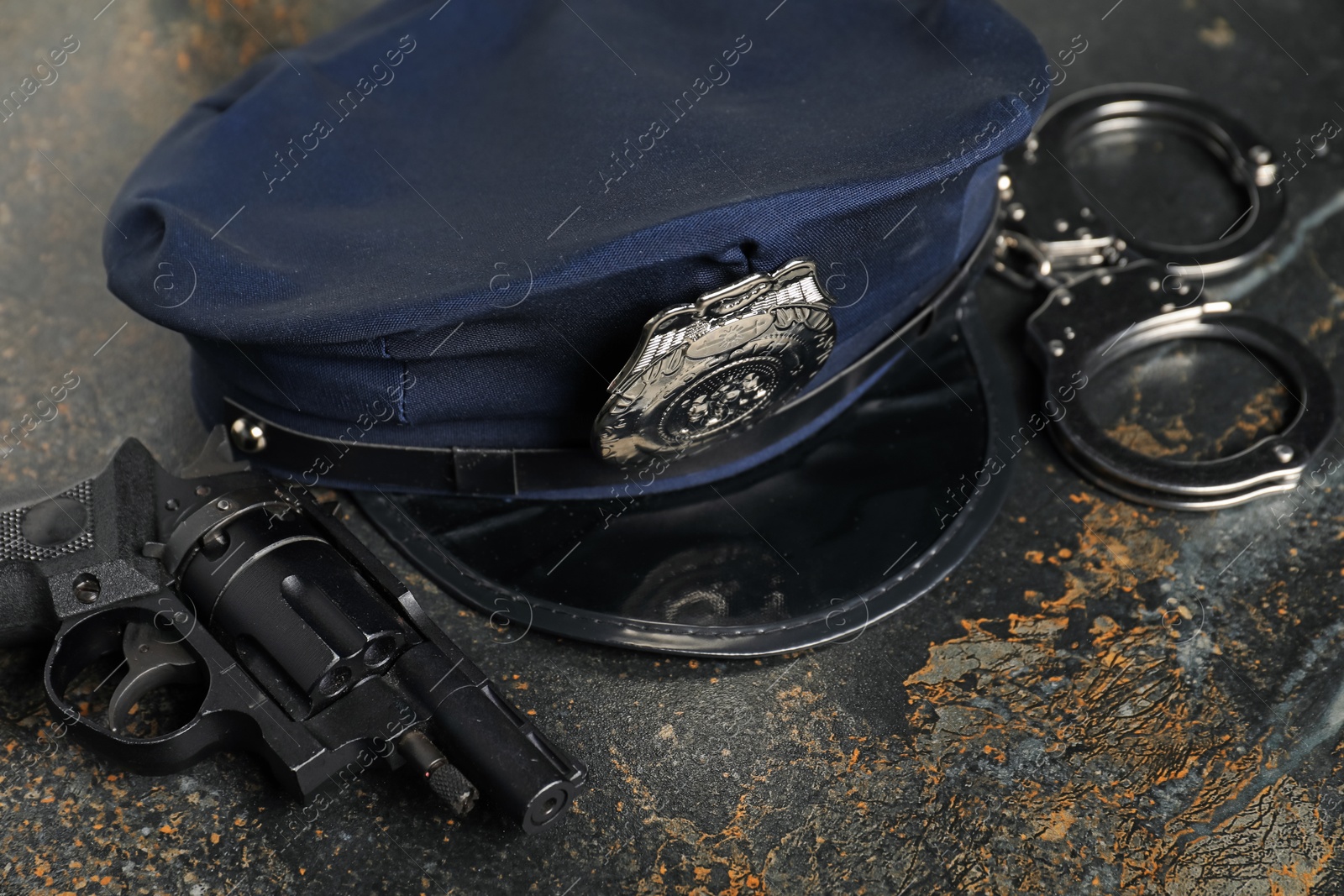 Police cap, handcuffs and gun on dark table, closeup Photo of Police cap, handcuffs and gun on dark table, closeup