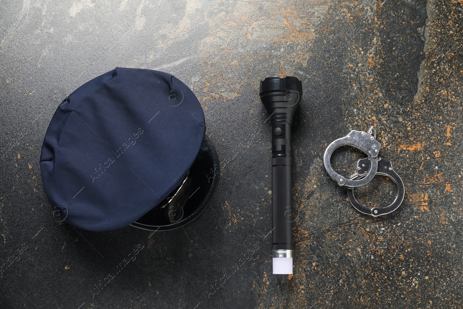 Police cap, flashlight and handcuffs on dark table, flat lay Photo of Police cap, flashlight and handcuffs on dark table, flat lay