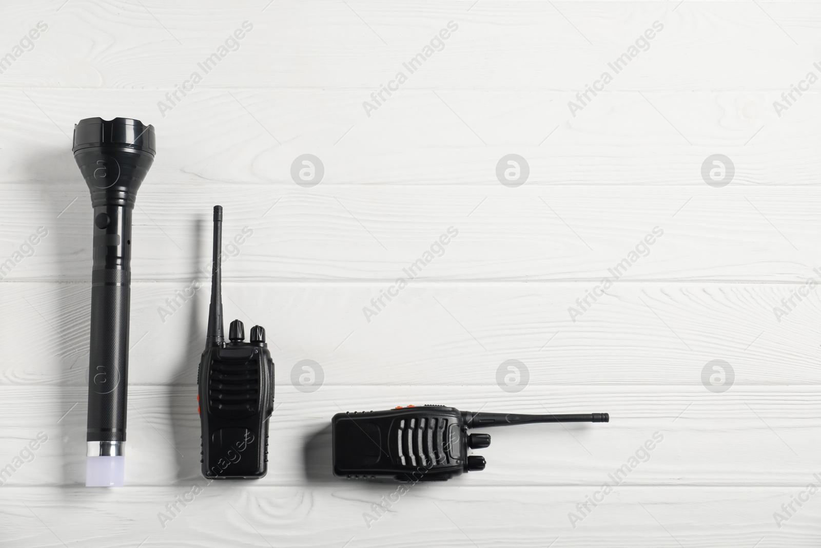 Police equipment. Flashlight and walkie talkies on white wooden table, flat lay. Space for text Photo of Police equipment. Flashlight and walkie talkies on white wooden table, flat lay. Space for text