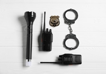 Photo of Different police equipment on white wooden table, flat lay