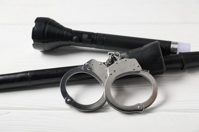 Photo of Flashlights and handcuffs on white wooden table, closeup. Police equipment