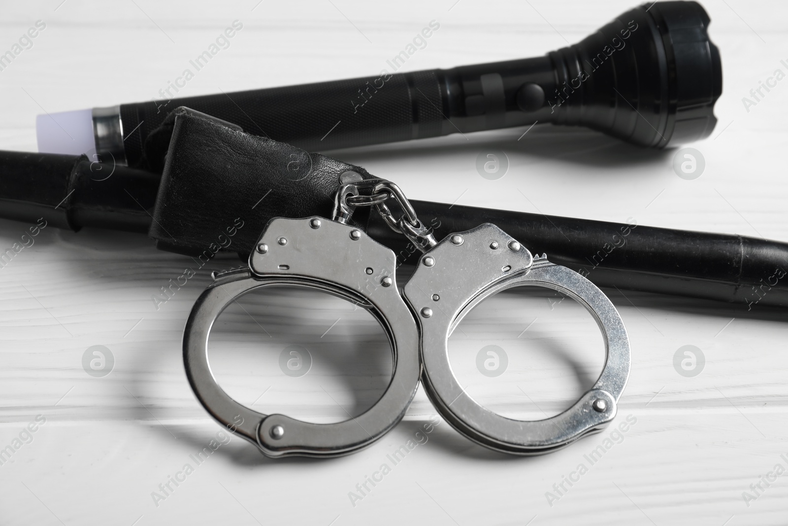Flashlights and handcuffs on white wooden table, closeup. Police equipment Photo of Flashlights and handcuffs on white wooden table, closeup. Police equipment