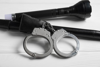 Photo of Flashlights and handcuffs on white wooden table, closeup. Police equipment