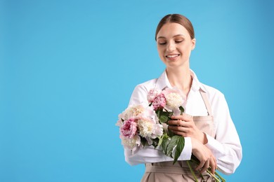 Photo of Florist with beautiful bouquet of peonies on light blue background, space for text