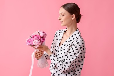 Photo of Woman with beautiful bouquet of peonies on pink background