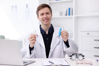 Photo of Portrait of professional ophthalmologist with eye drops at white table in clinic