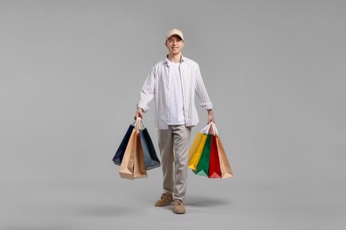 Photo of Cheerful man with shopping bags on light grey background