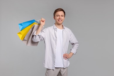 Photo of Cheerful man with shopping bags on light grey background