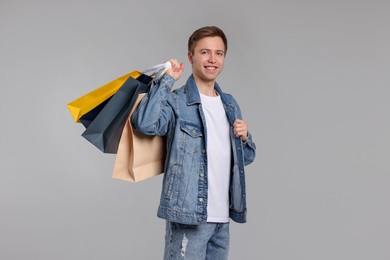 Photo of Cheerful man with shopping bags on light grey background