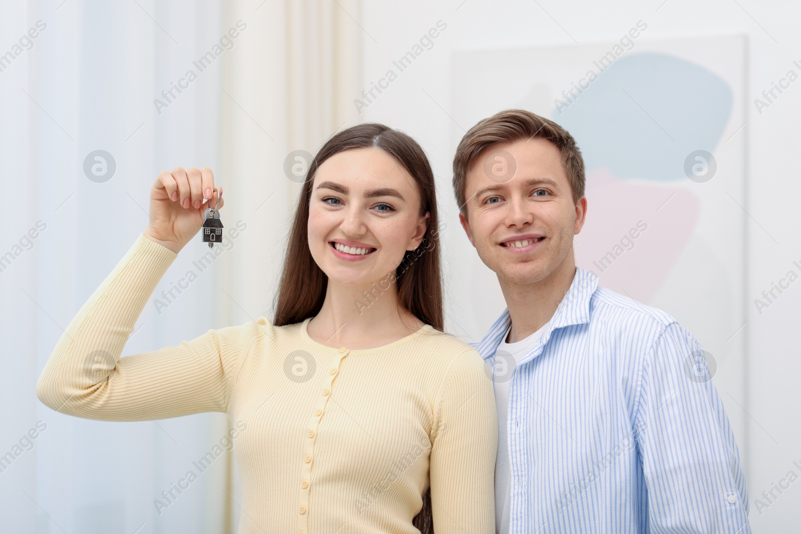Happy couple with key of their new house indoors Photo of Happy couple with key of their new house indoors