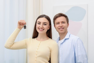 Photo of Happy couple with key of their new house indoors