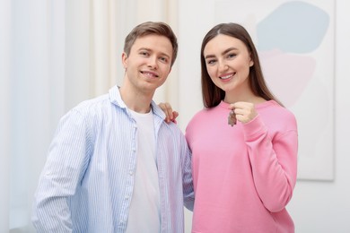 Photo of Happy couple with key of their new apartment indoors